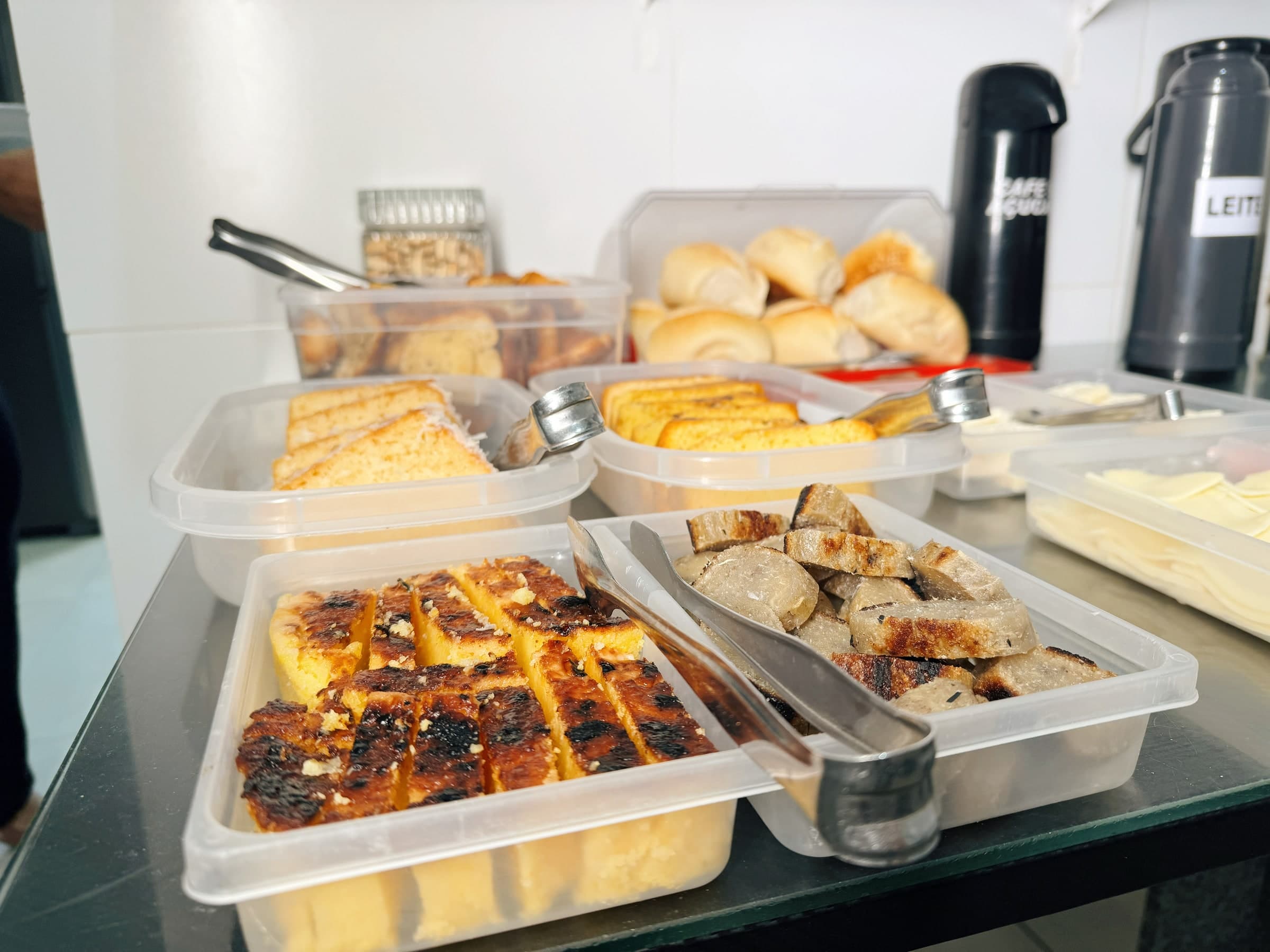 Mesa do café da manhã com bolos, pães, cuscuz e frios